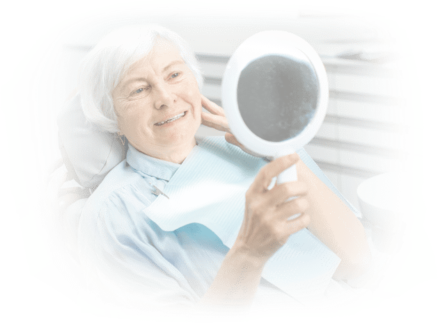 Elderly white-haired woman admiring her new smile with full arch dental implants in a mirror