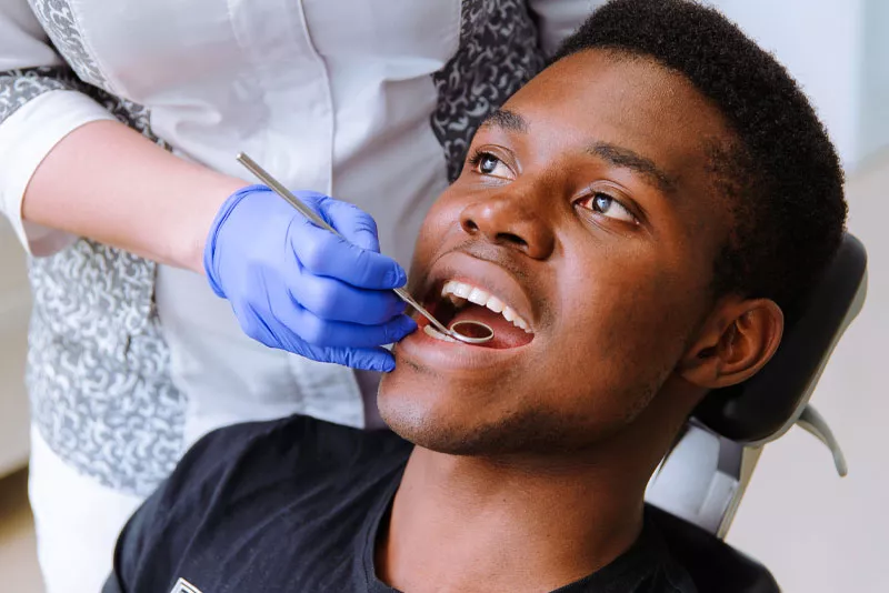 A Man Getting His Teeth Examined By The Dentist